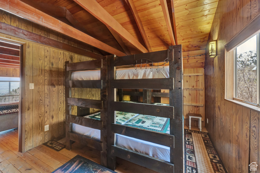Bedroom with wood ceiling, hardwood / wood-style floors, lofted ceiling with beams, and wooden walls