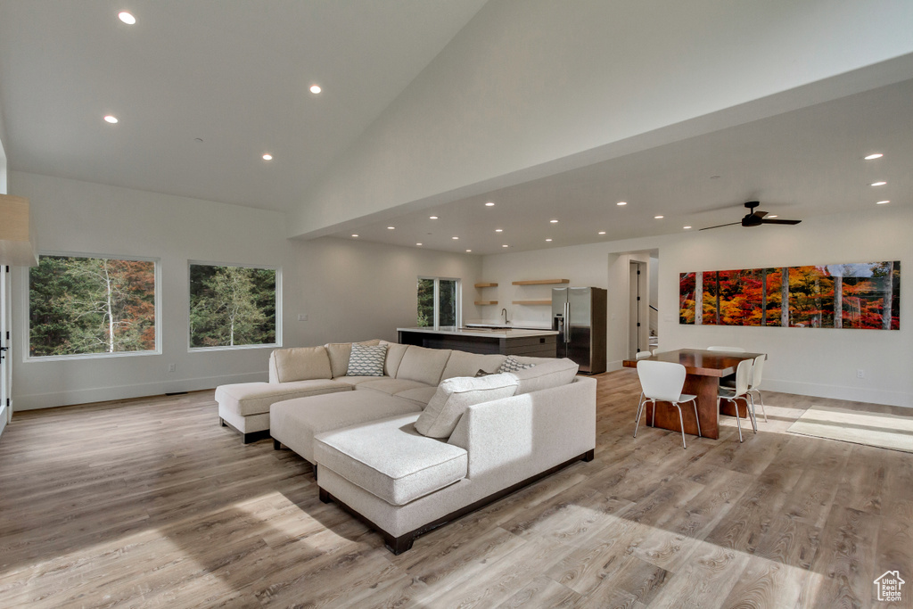 Living room featuring high vaulted ceiling, light hardwood / wood-style flooring, and ceiling fan
