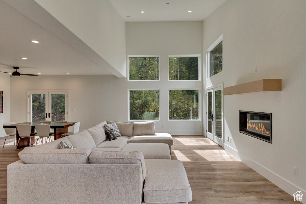 Living room with light hardwood / wood-style flooring, a wealth of natural light, and a towering ceiling