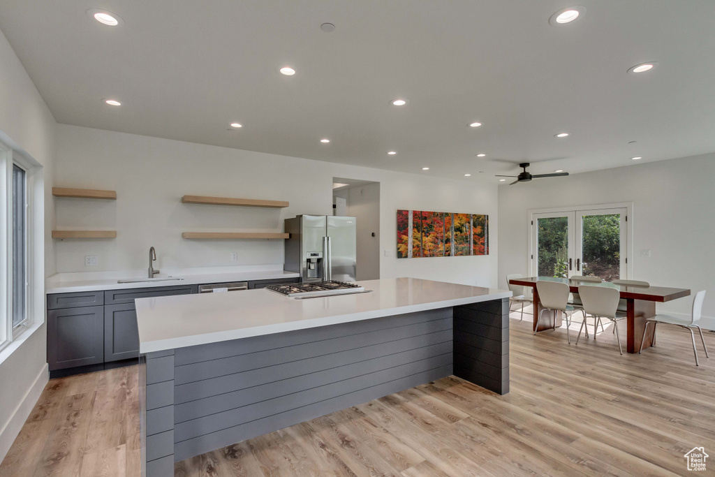 Kitchen with a kitchen island, gray cabinets, stainless steel appliances, ceiling fan, and light wood-type flooring