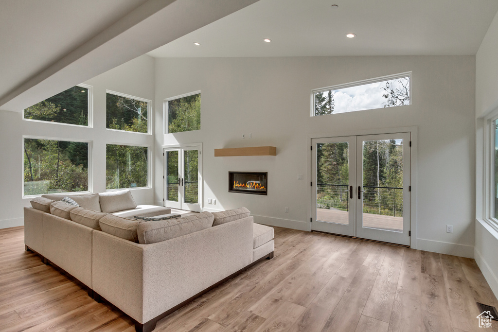 Living room featuring high vaulted ceiling, french doors, and light wood-type flooring