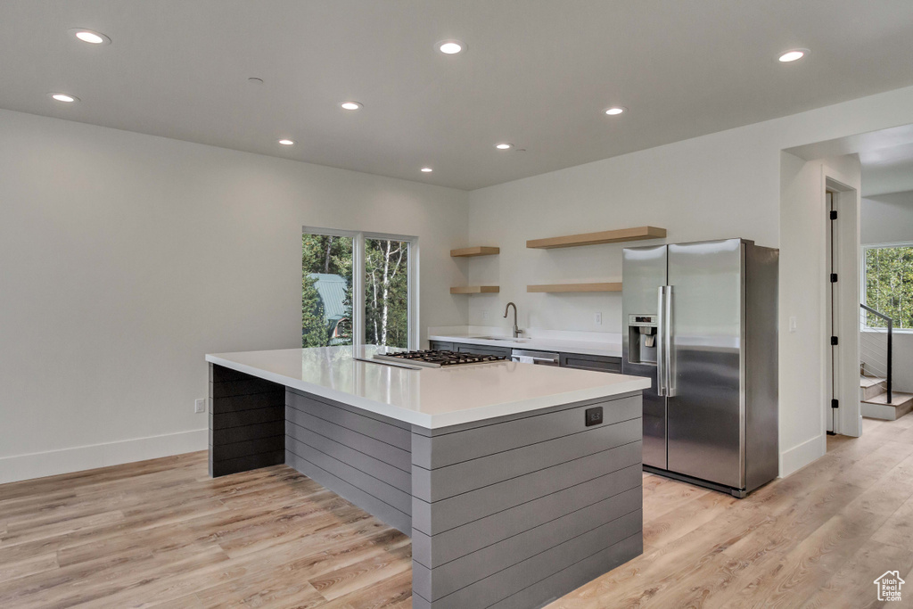 Kitchen with a center island, appliances with stainless steel finishes, and light hardwood / wood-style floors