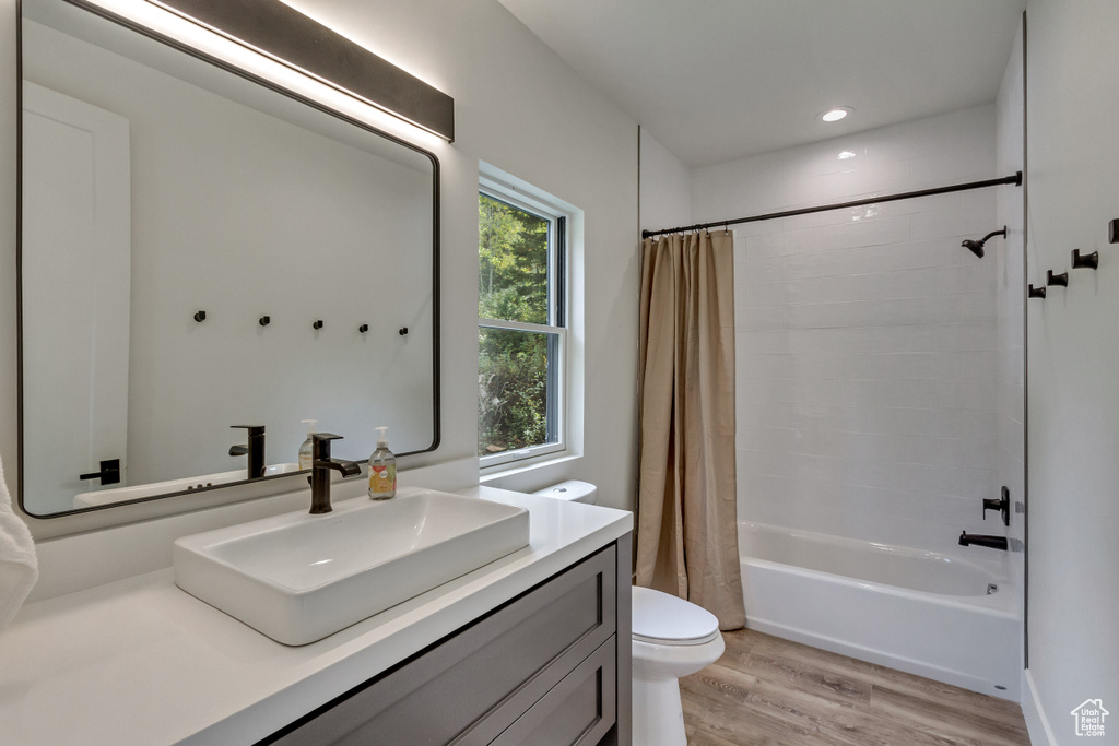 Full bathroom featuring hardwood / wood-style floors, shower / tub combo, vanity, and toilet