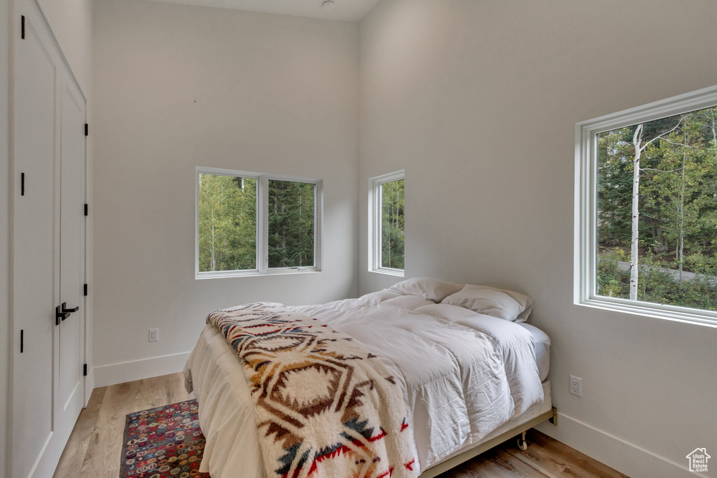 Bedroom with multiple windows, hardwood / wood-style flooring, and a towering ceiling