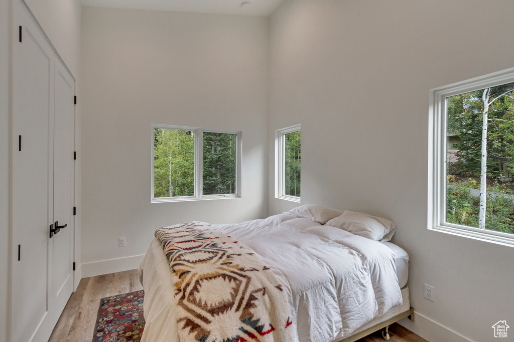 Bedroom with hardwood / wood-style flooring, high vaulted ceiling, and multiple windows