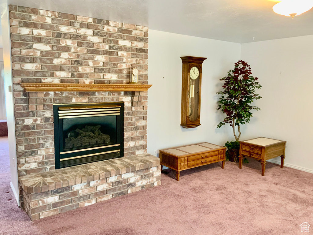 Carpeted living room with brick wall and a fireplace