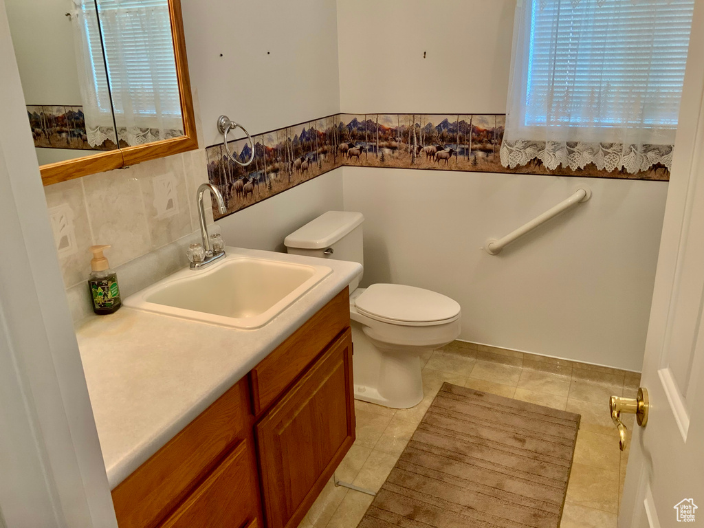 Bathroom featuring tasteful backsplash, vanity, toilet, and tile flooring
