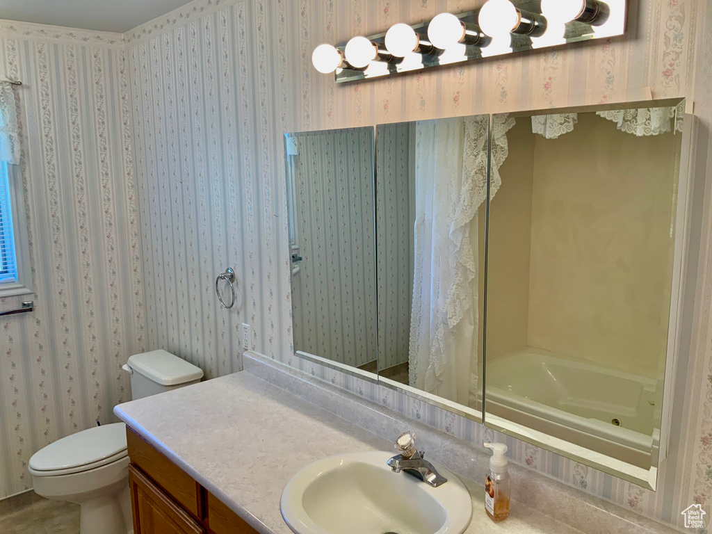Full bathroom featuring oversized vanity, shower / bath combo, and toilet