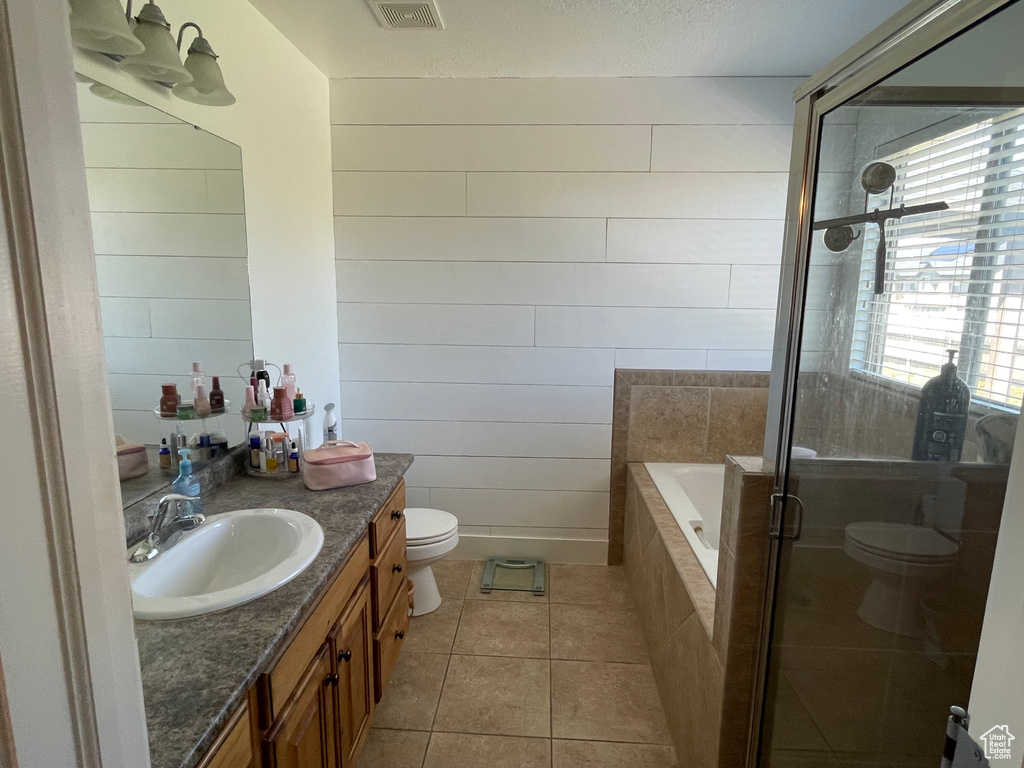 Bathroom with tile flooring, vanity, toilet, and tiled bath