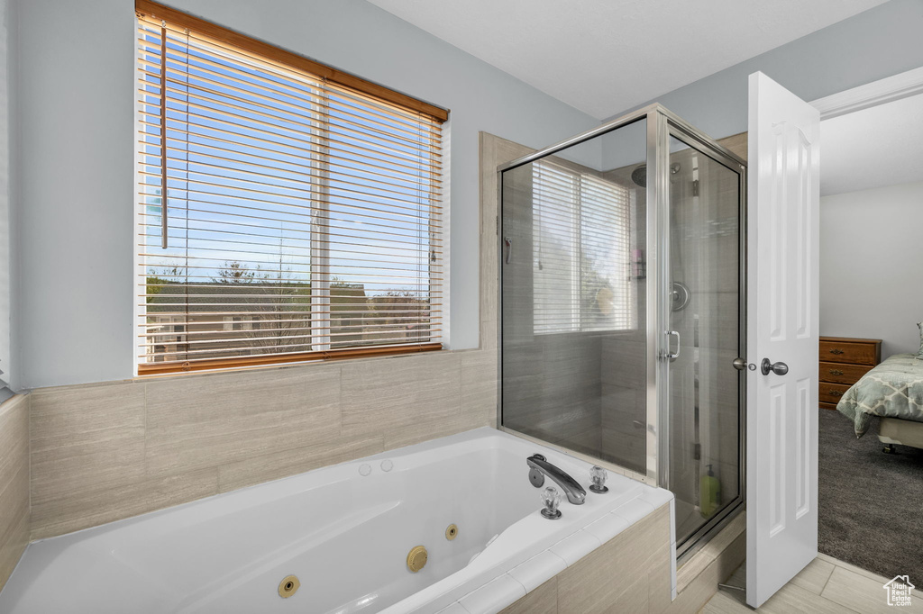 Bathroom featuring a healthy amount of sunlight, tile flooring, and separate shower and tub