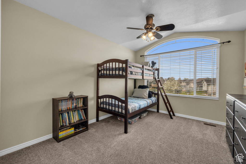 Bedroom with ceiling fan, vaulted ceiling, and carpet flooring