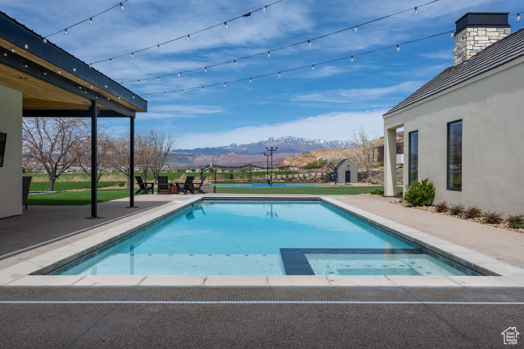 View of swimming pool with a patio area, a mountain view, and an in ground hot tub