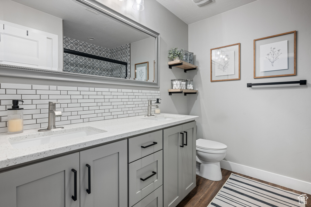 Bathroom featuring hardwood / wood-style floors, tasteful backsplash, toilet, and dual vanity