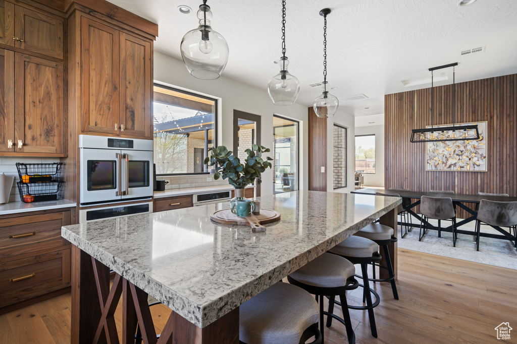 Kitchen with hanging light fixtures, light hardwood / wood-style floors, and a center island
