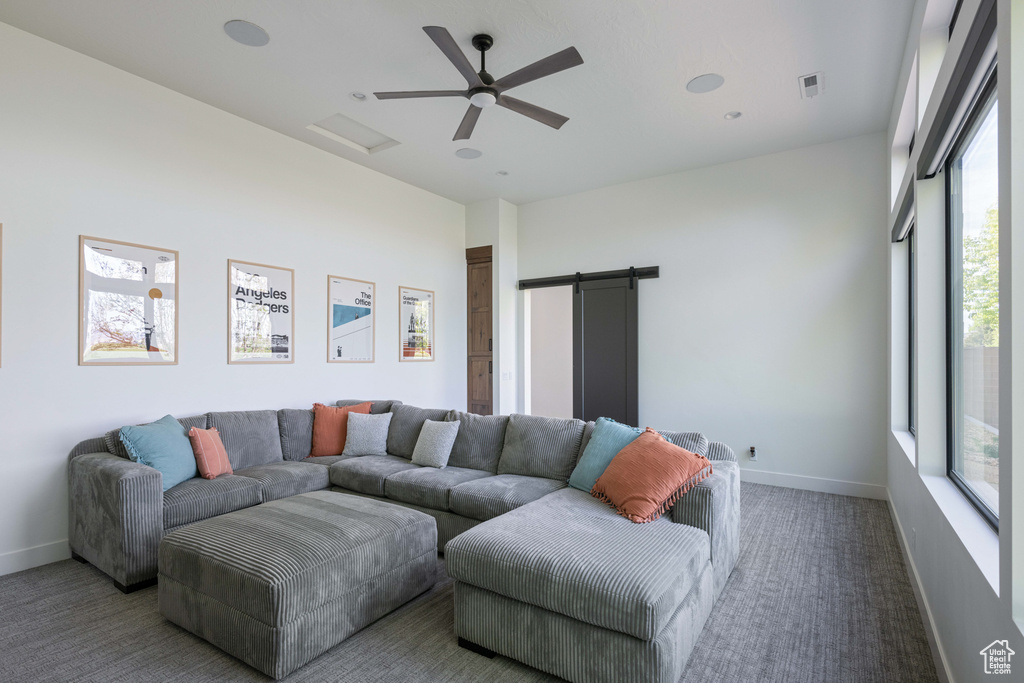 Carpeted living room featuring ceiling fan and a barn door