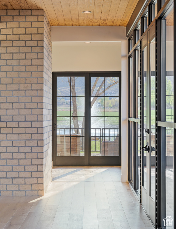 Entryway featuring wood ceiling, french doors, and brick wall