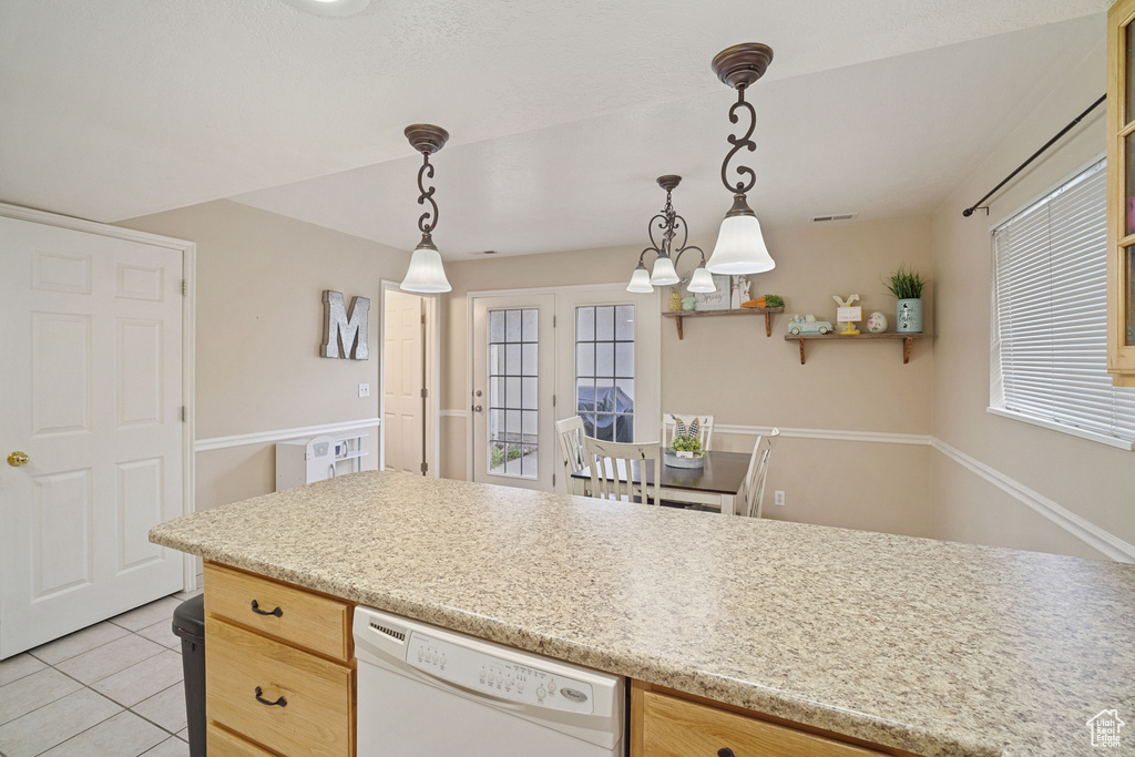 Kitchen with decorative light fixtures, dishwasher, light tile floors, and light stone countertops