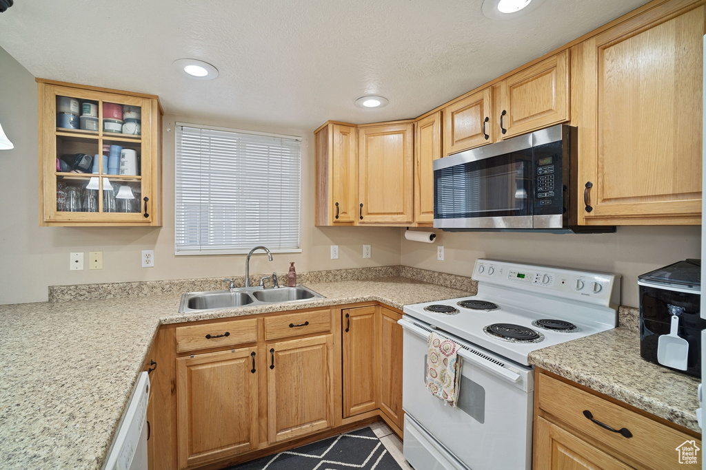 Kitchen featuring white appliances, light stone countertops, light brown cabinets, light tile floors, and sink