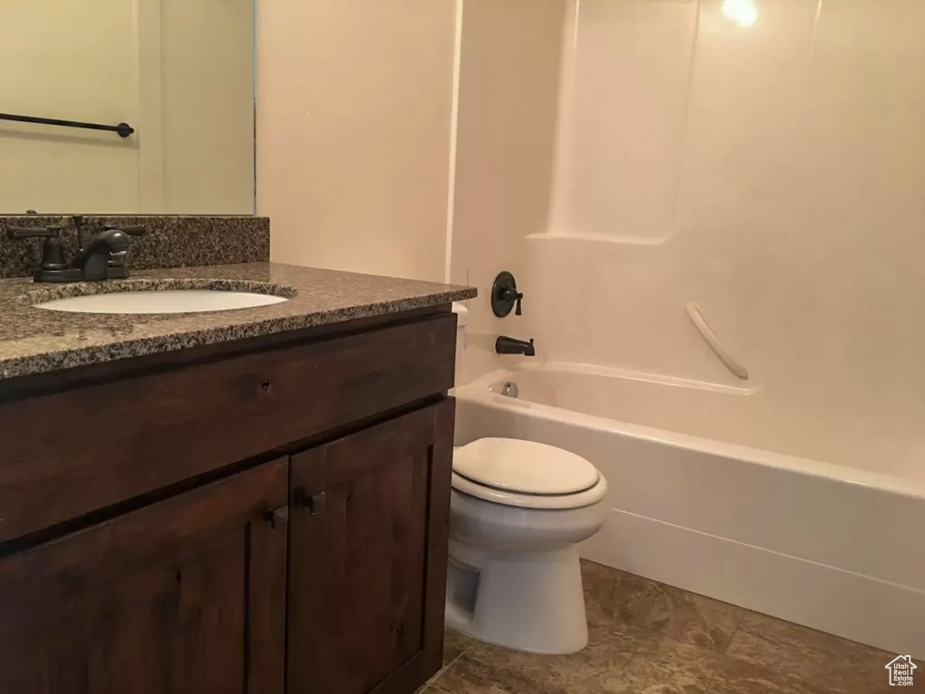 Full bathroom featuring tile floors, oversized vanity, toilet, and washtub / shower combination