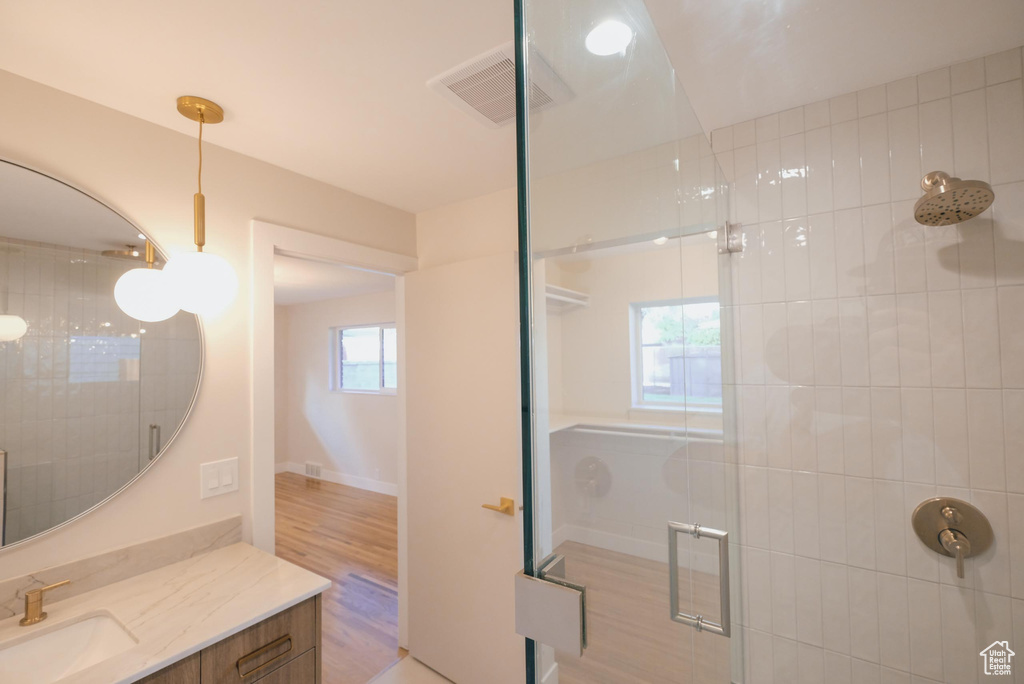 Bathroom featuring hardwood / wood-style flooring, a shower with shower door, and vanity
