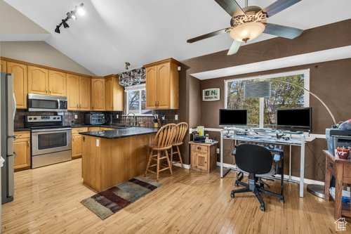 Kitchen featuring ceiling fan, rail lighting, range with electric stovetop, light hardwood / wood-style flooring, and kitchen peninsula
