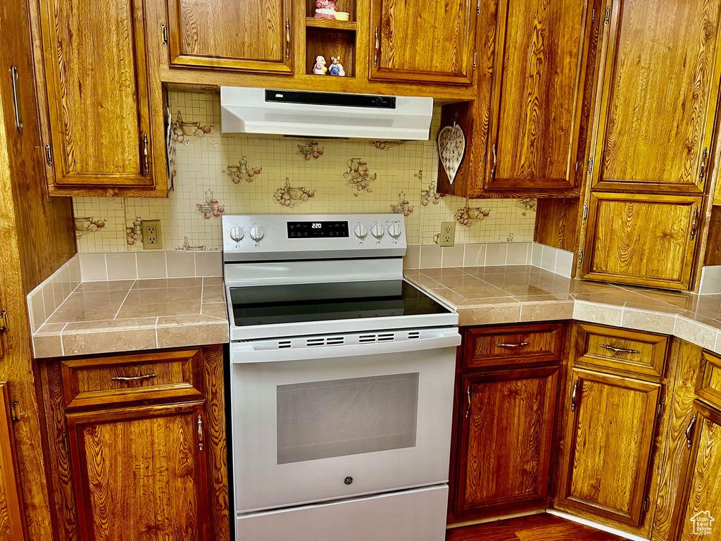 Kitchen with backsplash, tile countertops, hardwood / wood-style flooring, and white range with electric stovetop
