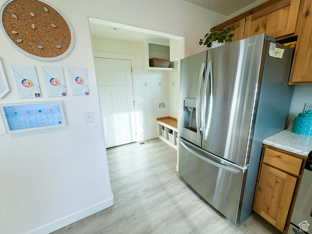 Kitchen with stainless steel refrigerator with ice dispenser and light wood-type flooring