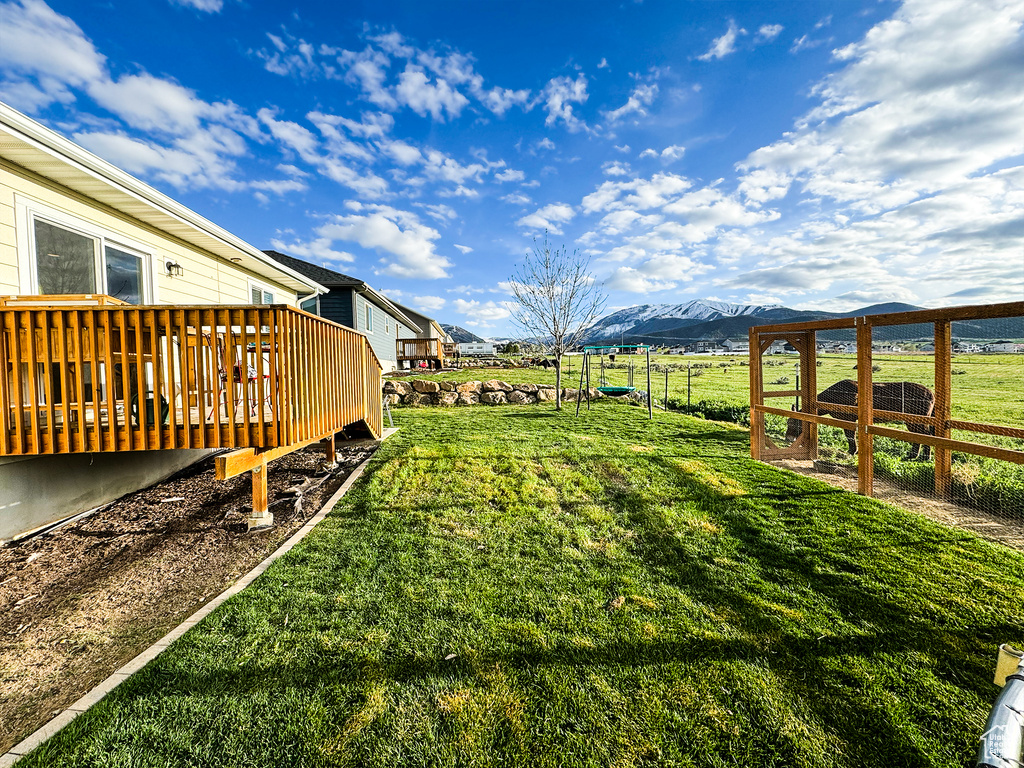 View of yard with a rural view and a deck with mountain view