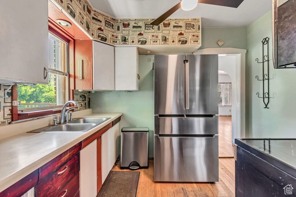 Kitchen featuring light hardwood / wood-style flooring, stainless steel fridge, ceiling fan, white cabinetry, and sink