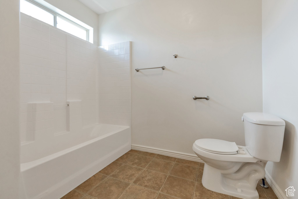 Bathroom with tile flooring, washtub / shower combination, and toilet