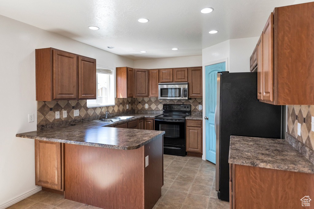 Kitchen with backsplash, light tile flooring, and black appliances