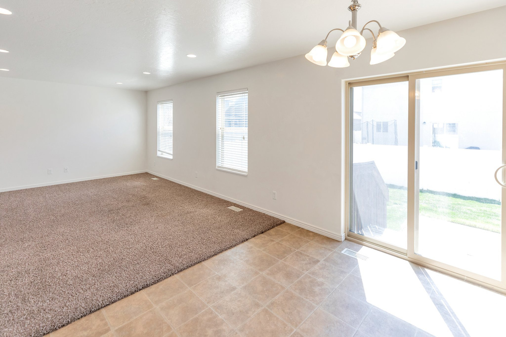 Empty room featuring a chandelier and light tile floors