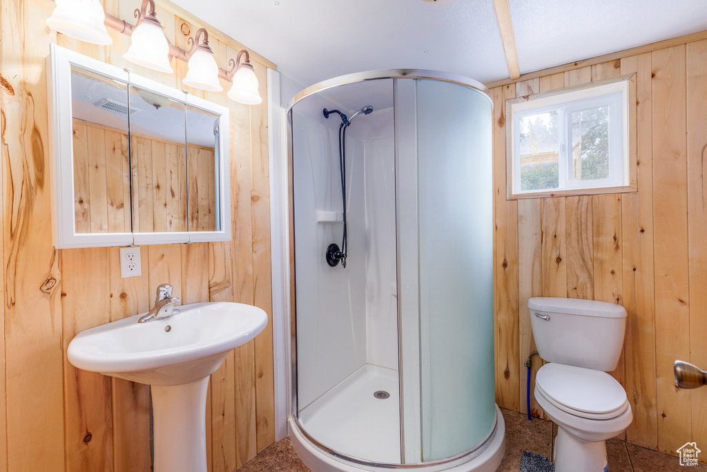 Bathroom with a shower with shower door, toilet, and wooden walls