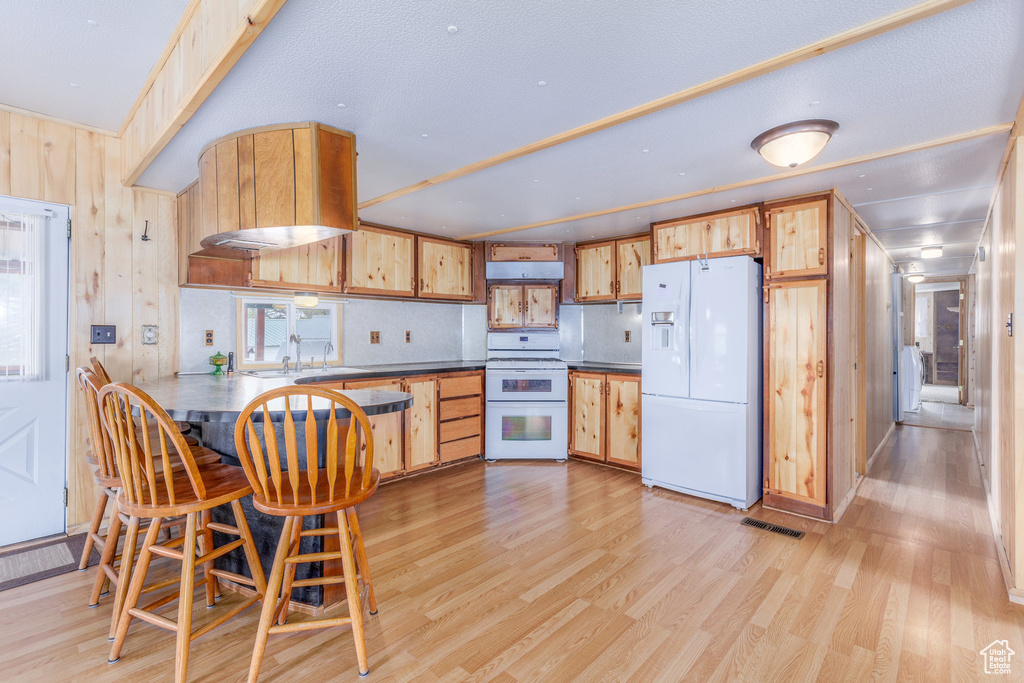 Kitchen featuring sink, white appliances, kitchen peninsula, and light wood-type flooring
