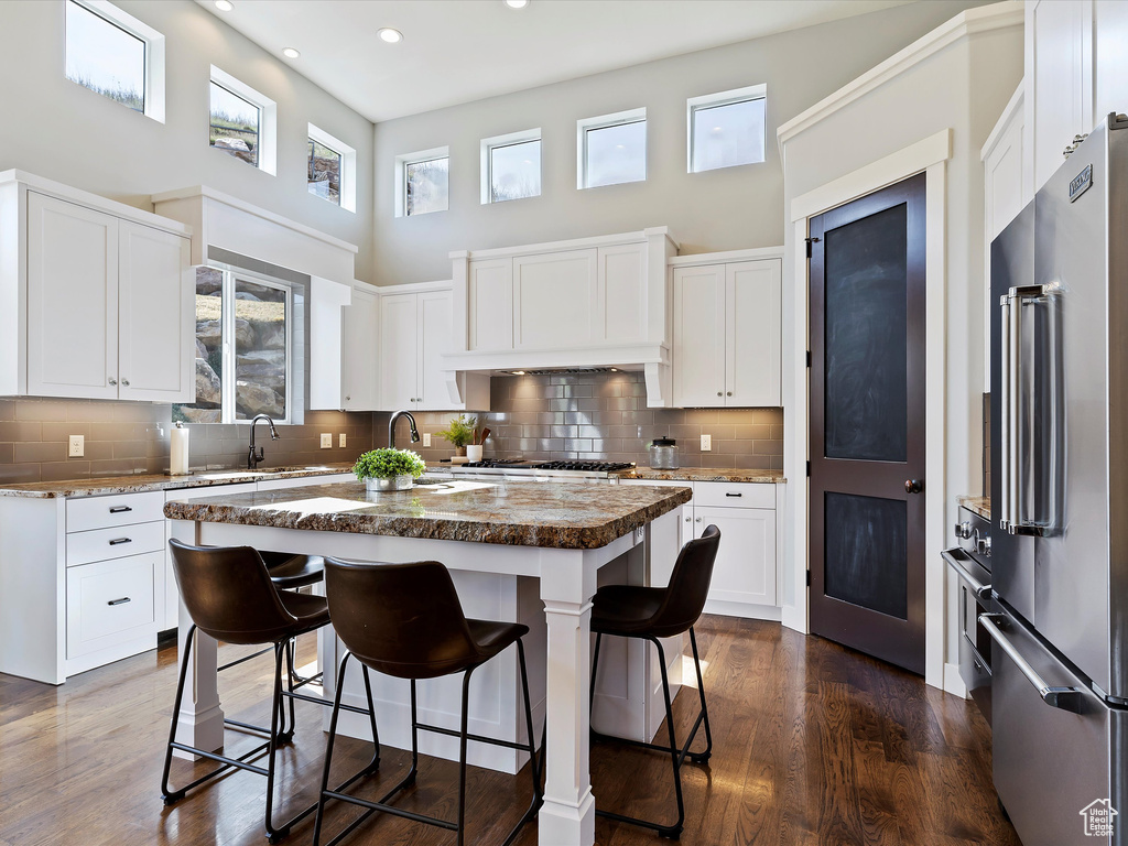 Kitchen featuring dark hardwood / wood-style flooring, high end fridge, backsplash, and a kitchen island