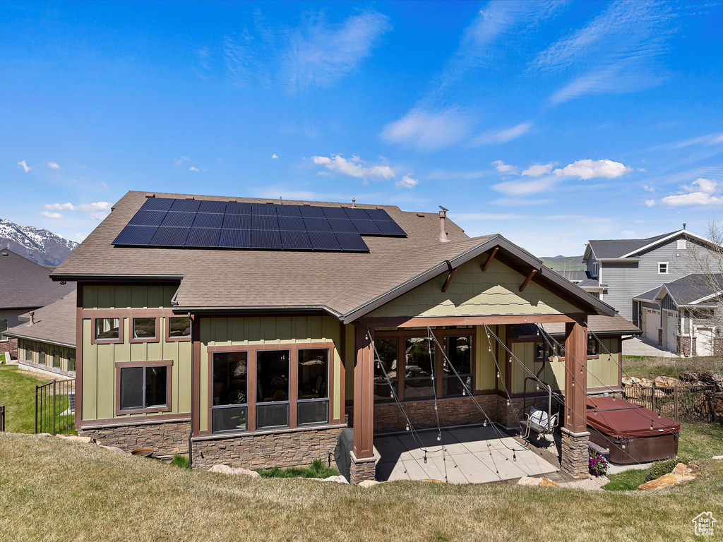 Rear view of property featuring solar panels, a yard, and a patio area