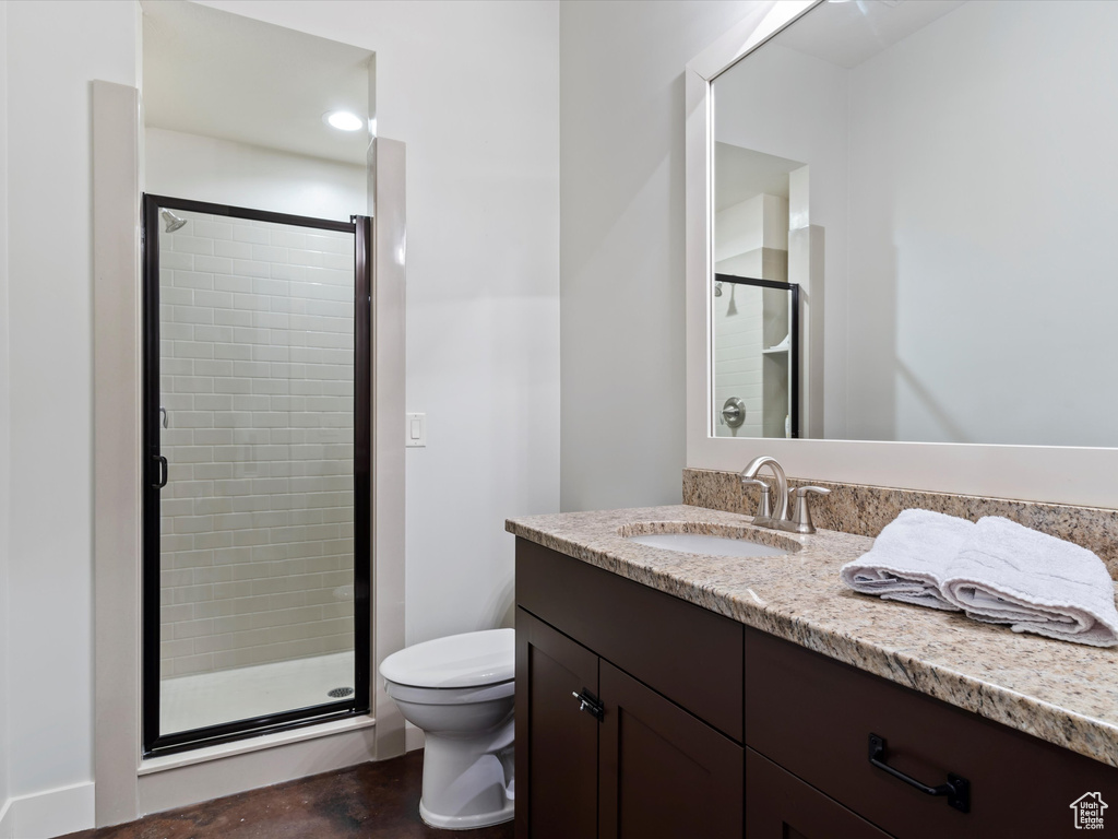Bathroom featuring walk in shower, vanity with extensive cabinet space, and toilet