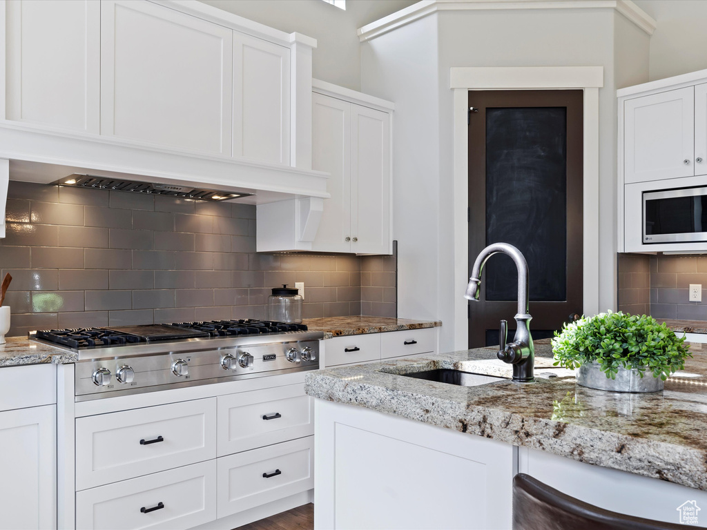 Kitchen featuring tasteful backsplash, stainless steel appliances, sink, and light stone countertops