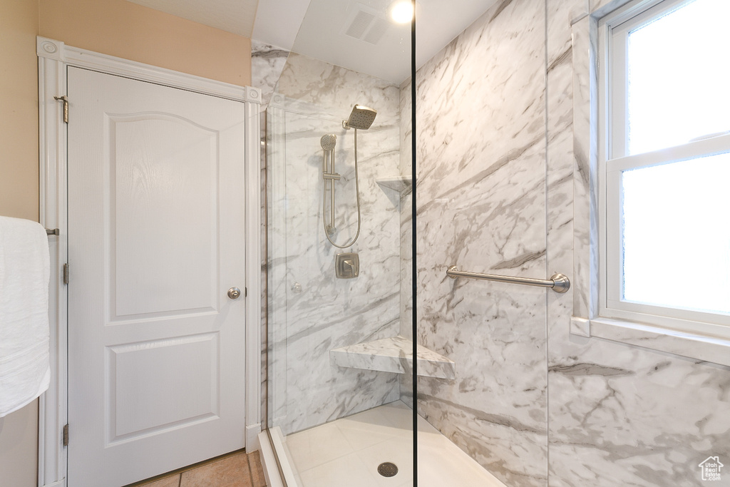 Bathroom with plenty of natural light, a shower with shower door, and tile flooring