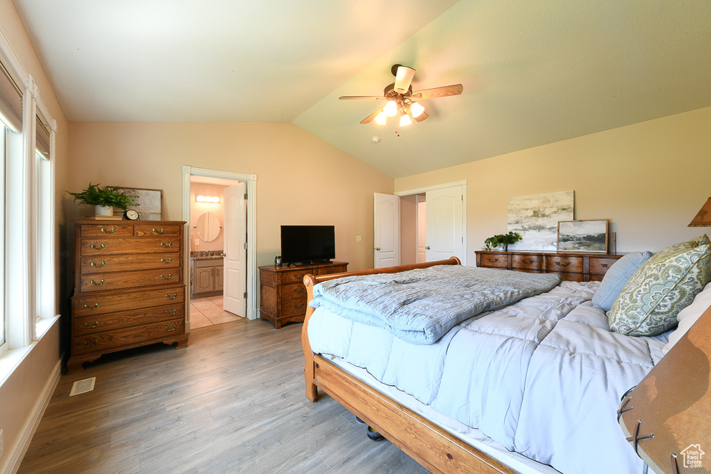 Bedroom featuring lofted ceiling, ensuite bath, ceiling fan, and light wood-type flooring