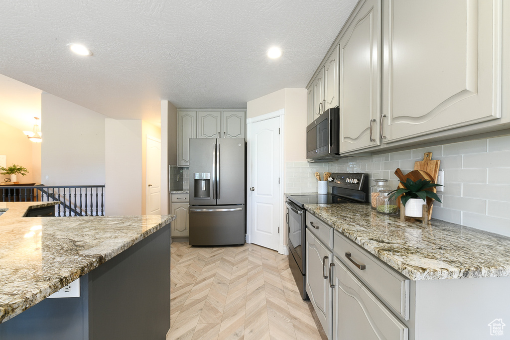 Kitchen featuring range with electric stovetop, stainless steel refrigerator with ice dispenser, light parquet flooring, tasteful backsplash, and gray cabinetry