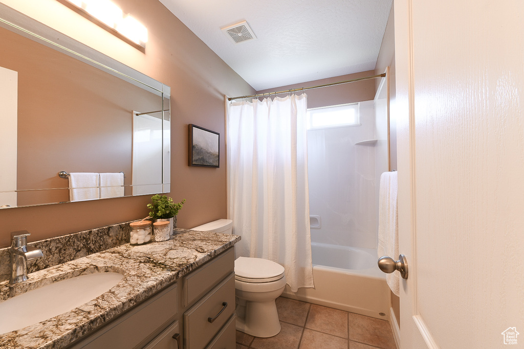 Full bathroom with tile floors, toilet, oversized vanity, and shower / bath combination with curtain