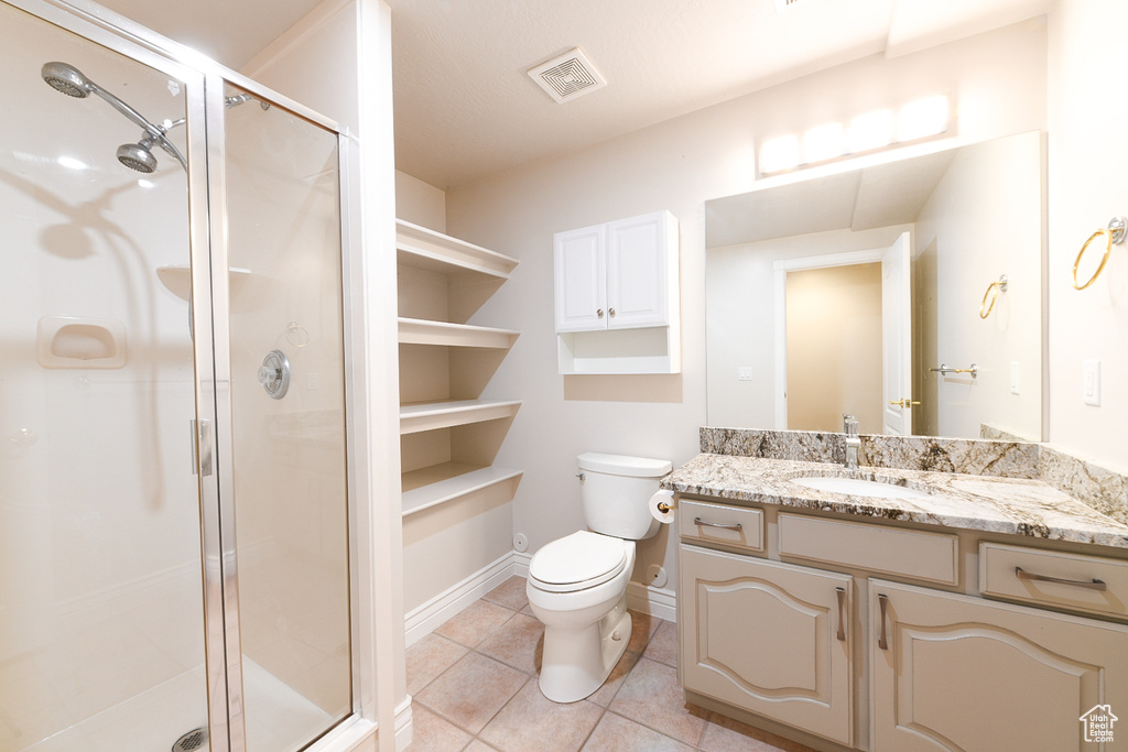 Bathroom with vanity with extensive cabinet space, toilet, tile flooring, and walk in shower