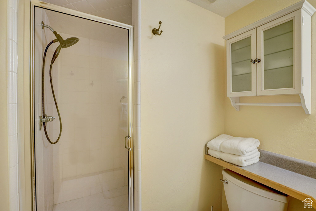 Bathroom featuring a shower with shower door and toilet