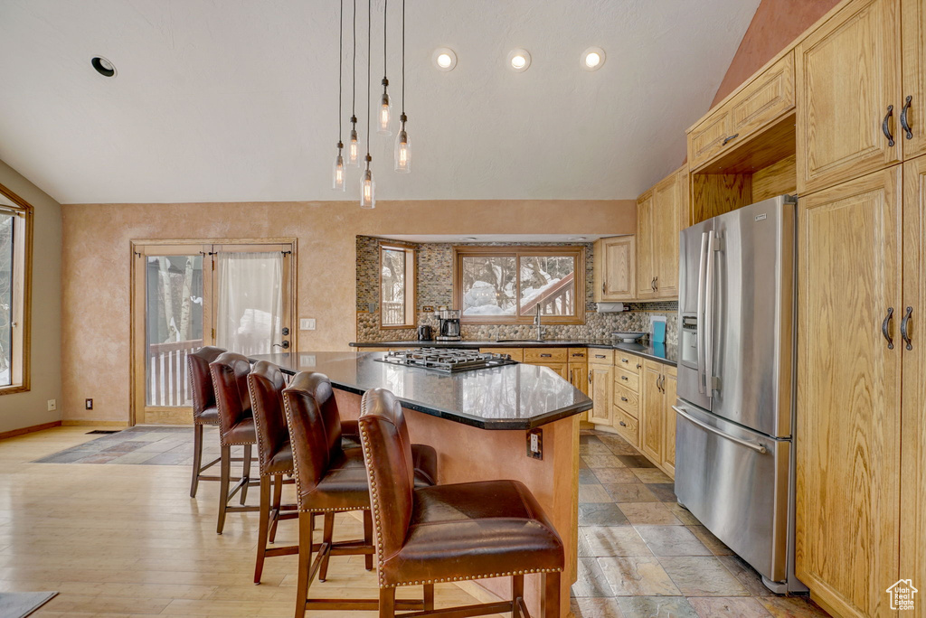 Kitchen with a breakfast bar, light wood-type flooring, stainless steel appliances, a kitchen island, and lofted ceiling