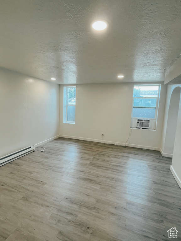 Unfurnished room with hardwood / wood-style floors, plenty of natural light, and a textured ceiling
