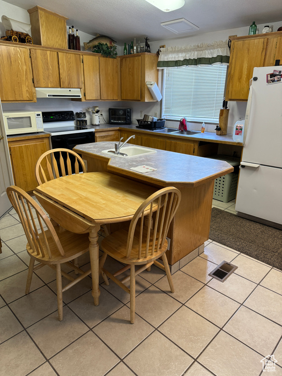 Kitchen featuring light tile flooring, white appliances, and sink