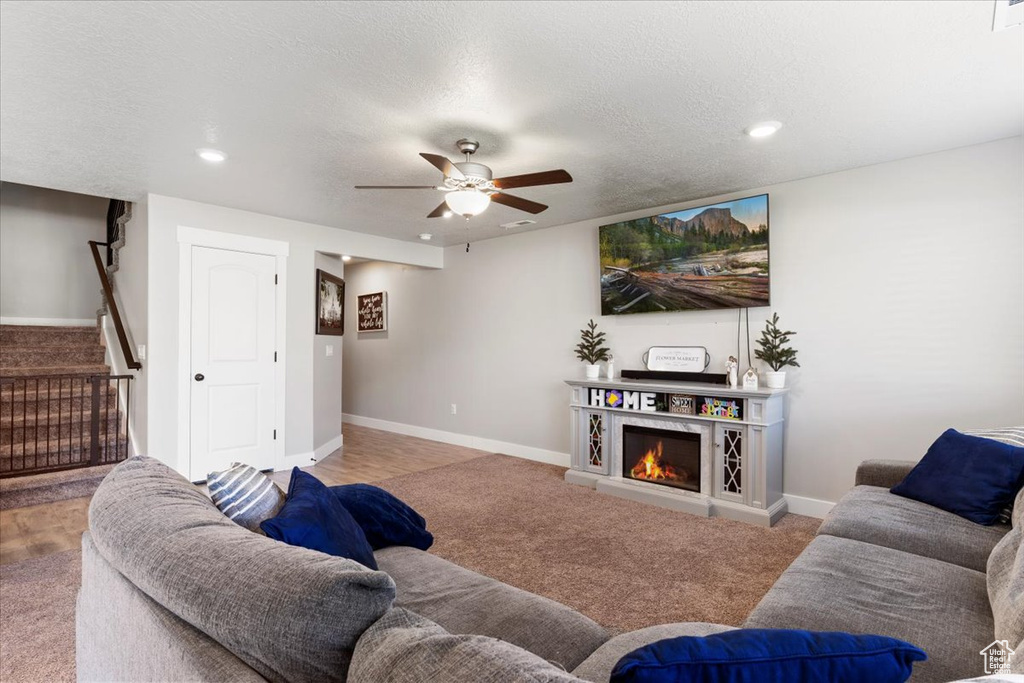 Living room with ceiling fan, carpet, and a textured ceiling