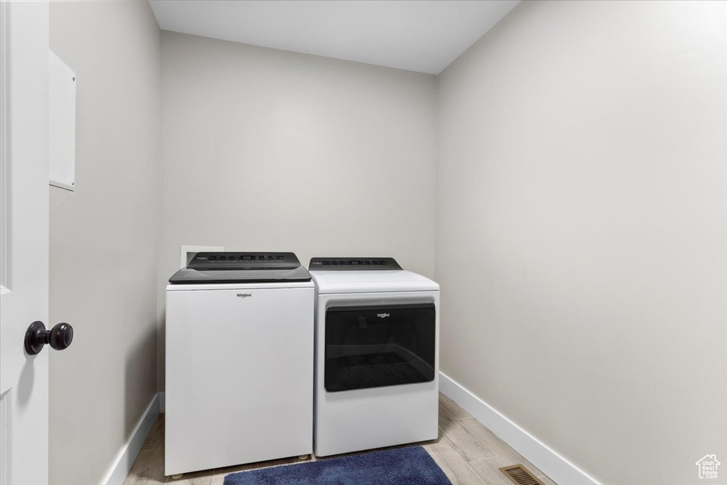 Laundry area featuring washer and clothes dryer and light hardwood / wood-style flooring