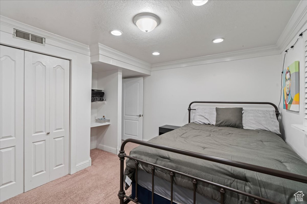 Bedroom with ornamental molding, a closet, carpet flooring, and a textured ceiling